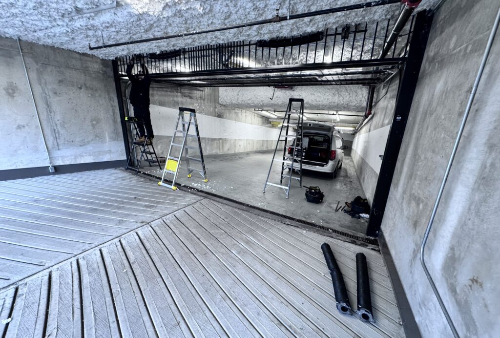 Technician repairs broken garage door spring on commercial parking gate. Master garage doors Vancouver